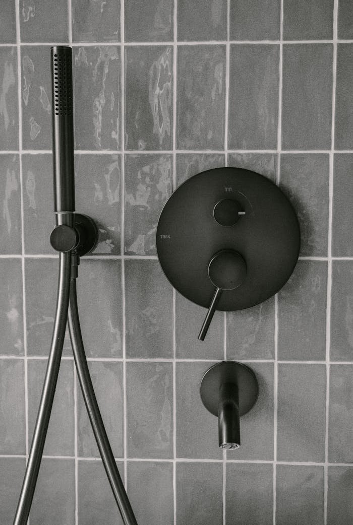 Stylish matte black shower fixtures on modern tiled wall, capturing minimalist bathroom design.