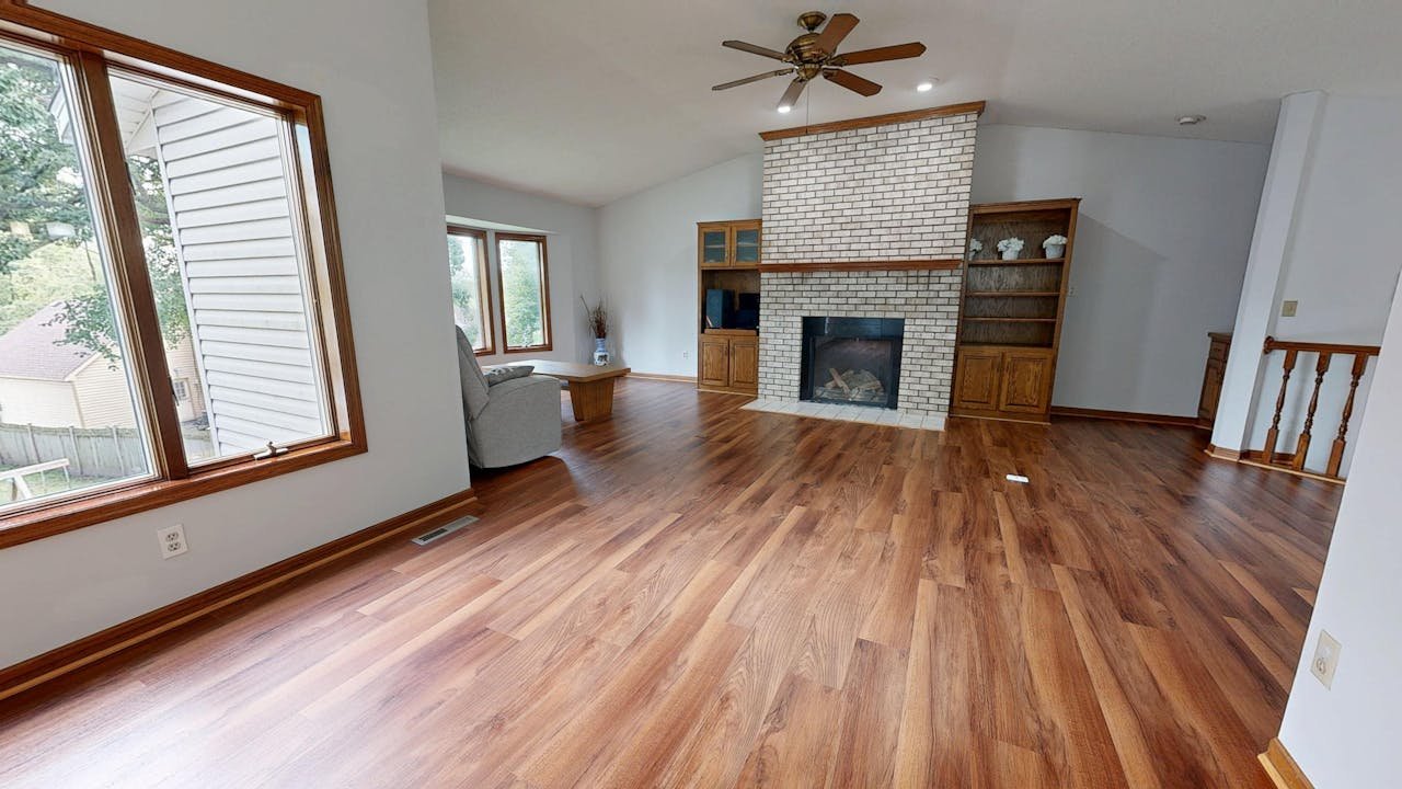 Bright living room featuring wood floors and a brick fireplace.