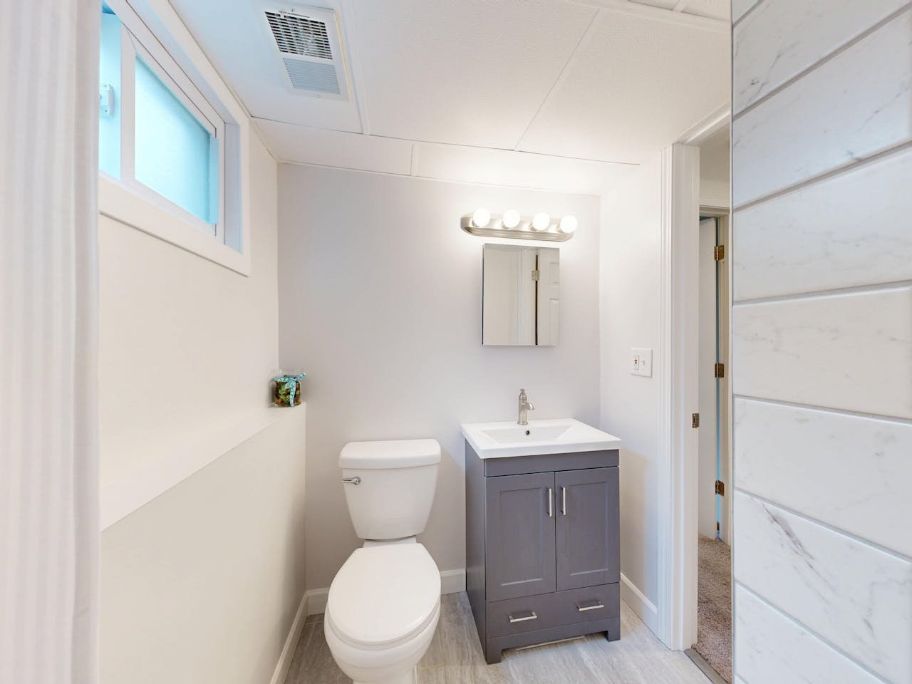 Bright modern bathroom interior with vanity, sink, and toilet in neutral colors.