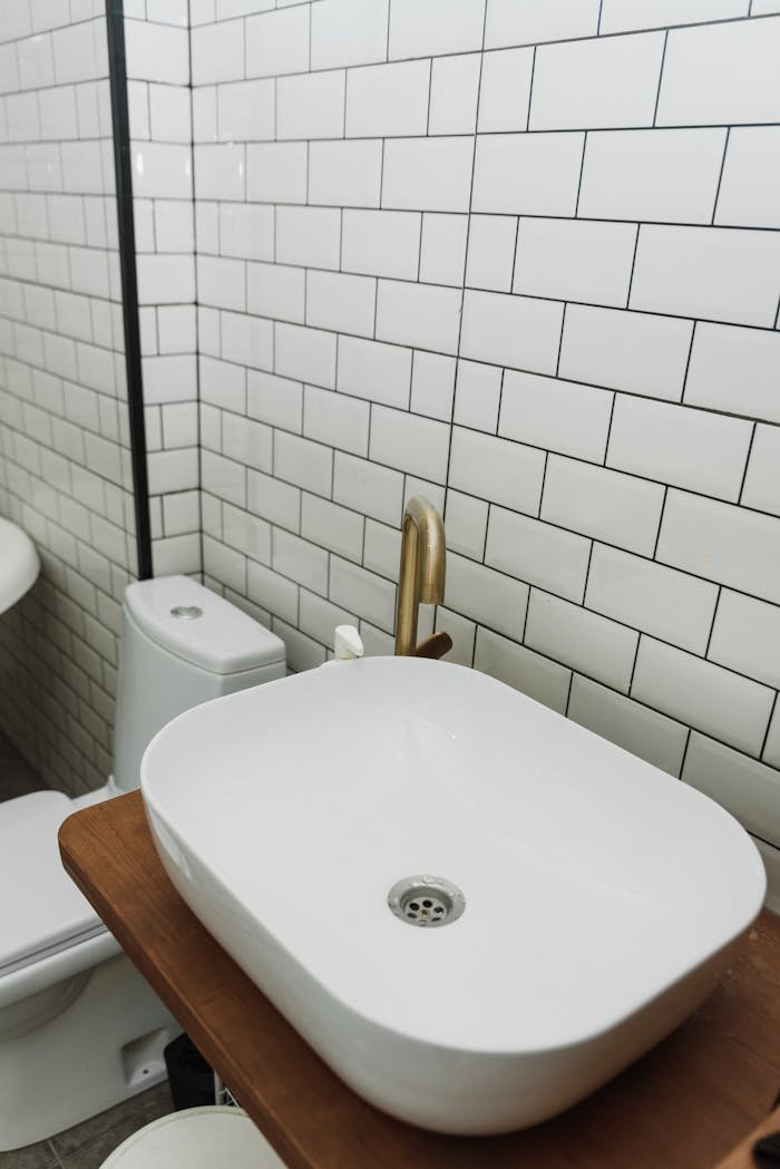 Stylish bathroom featuring a white ceramic sink with gold faucet and classic subway tiles.